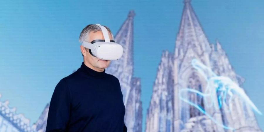 Vodafone-Chef Ametsreiter blickt mit einer Virtual-Reality-Brille auf den digitalen Zwilling des Kölner Doms. Foto: Rolf Vennenbernd/dpa