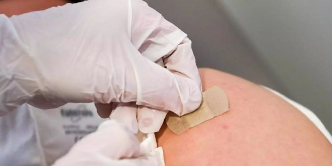 Eine Ärztin klebt nach einer Impfung ein Pflaster auf die Einstichstelle. Foto: Jens Kalaene/dpa-zentralbild/dpa coronavirus