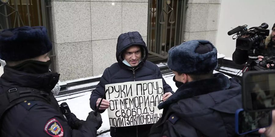 Polizeibeamte halten einen Demonstranten fest, der vor dem Obersten Gerichtshof der Russischen Föderation ein Plakat mit der Aufschrift «Hände weg von Memorial, Freiheit für politische Gefangene» hält. Foto: Pavel Golovkin/AP/dpa