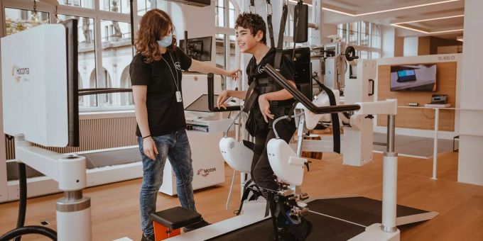 Nataniel mit einer Roboter-Gehhilfe. Nexttherapy