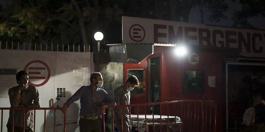 Arbeiter warten nach einer Explosion an der Eidgah-Moschee vor dem Emergency NGO Krankenhaus. Foto: Felipe Dana/AP/dpa