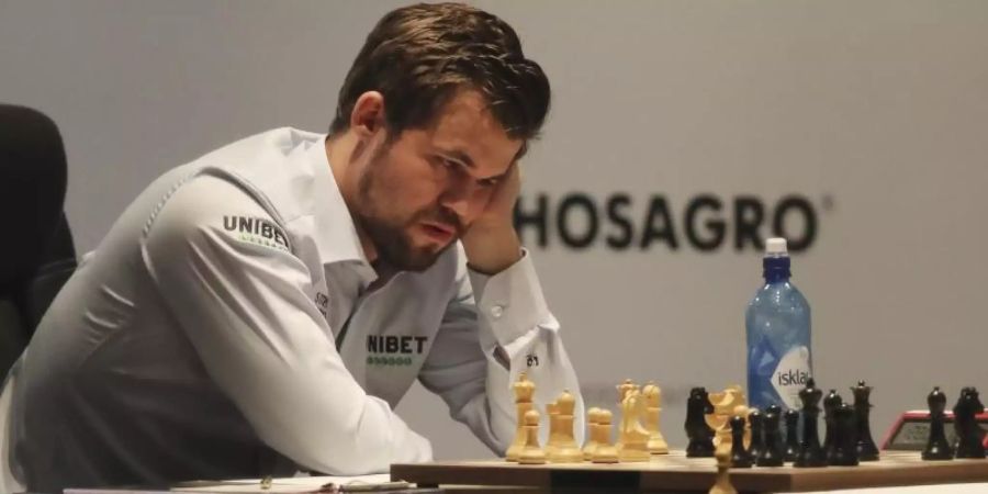 Magnus Carlsen studiert während des Spiels die Figuren auf dem Brett. Foto: Kamran Jebreili/AP/dpa