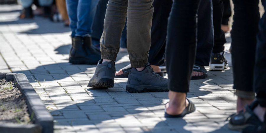 Asylbewerber stehen in einer Erstaufnahme-Einrichtung in Brandenburg in einer Schlange.