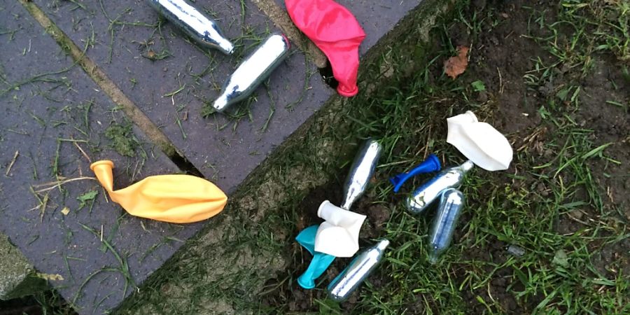 ARCHIV - Lachgas-Kartuschen und Luftballons liegen in einem Park im Londoner Stadtteil Shoreditch. Die britische Regierung will den Konsum von Lachgas eindämmen - zum Jahresende soll die Substanz als Droge verboten werden. Foto: Teresa Dapp/dpa