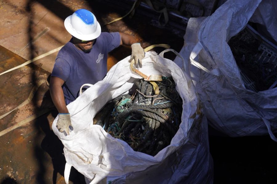 Der Grossteil des Plastiks im North Pacific Garbage Patch kann auf die Fischerei zurückgeführt werden. Im Bild: Ein Besatzungsmitglied des Segelfrachtschiffs Kwai des Ocean Voyages Institute bereitet einen Sack mit Plastik und Müll vor, der während des Entladens in Sausalito, Kalifornien, am Mittwoch, 27. Juli 2022, aus einem Laderaum gehoben werden soll.