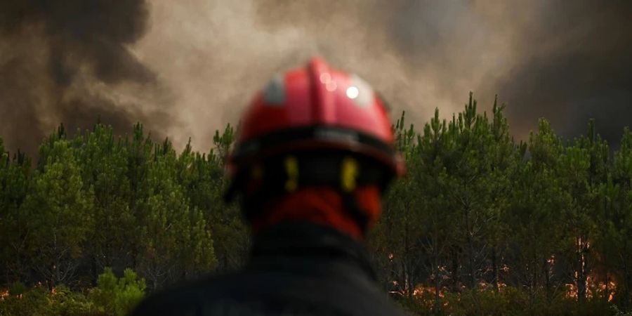 Ein Feuerwehrman vor einem brennenden Wald in Frankreich