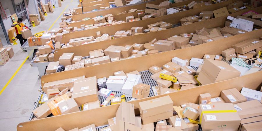 Ein Paketzusteller sortiert und räumt in einer Zustellbasis von Deutsche Post DHL Pakete in ein Zustellfahrzeug.