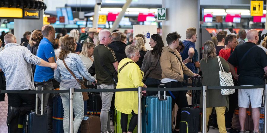 Reisende stehen in der Abflughalle des Amsterdamer Flughafens Schiphol Schlange.
