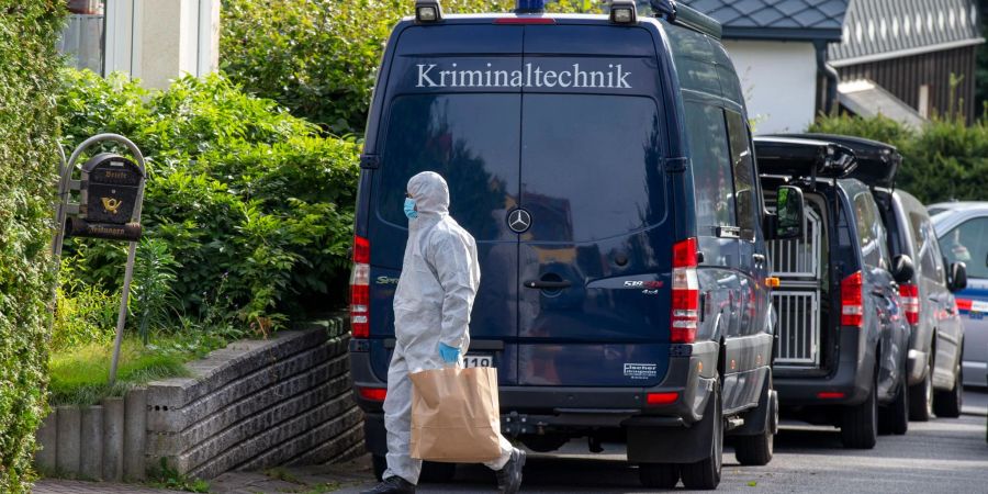 Ein Polizeibeamter läuft 2021 mit einer Papiertüte an einem Fahrzeug der Kriminaltechnik vorbei. Ermittelt wurde im Fall einer getöteten Jugendlichen.