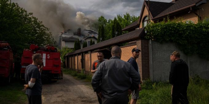Nachbarn versammeln sich in Charkiw um ein brennendes Haus, das bei einem russischen Angriff mit Streumunition getroffen wurde. streumunition