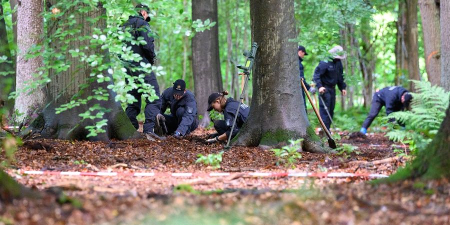 Polizeibeamte durchforsten mit Metalldetektoren und Schaufeln den in Planquadrate aufgeteilten Waldboden in Norderstedt.