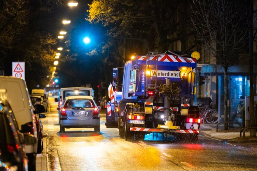 Autos im Stadtverkehr überholen ein Winterdienst Fahrzeug mit Salzustreuer. Nach der Glättegefahr des Vortags hat sich die Situation im Frankfurter Vorort Höchst deutlich entspannt.