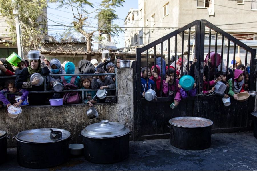 Menschen warten im Flüchtlingslager in Rafah auf Essensverteilung.