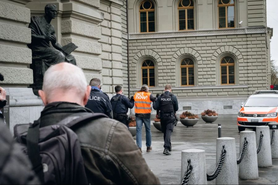 Die Polizei führt den Aktivisten nach seiner Bundeshaus-Schmiererei ab.