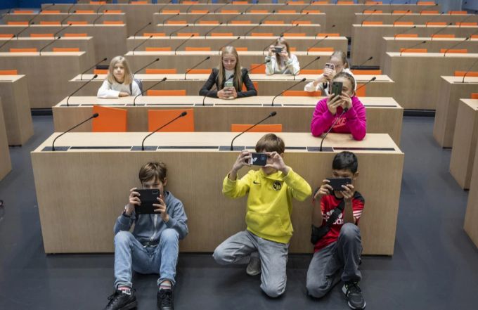 Jungen und Mädchen sind im grossen Konferenzraum des Bundeshauses zu Besuch. Bundeshaus