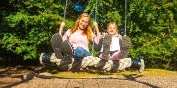 Kind mit Mutter auf Schaukel