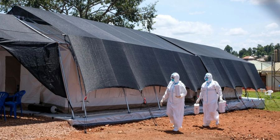 Zwei Ärzte in Schutzanzügen gehen zum Ebola-Isolationsbereich des Mubende Regional Referral Hospital. Im ostafrikanischen Uganda ist die Zahl neuer Infektionen mit dem tödlichen Ebola-Virus über das Wochenende rasant angestiegen.