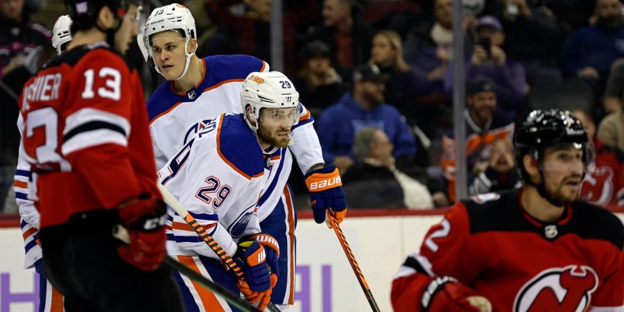 Leon Draisaitl (M) von den Edmonton Oilers reagiert nach einem Tor von Nico Hischier (l) von den New Jersey Devils.