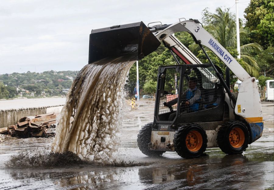 Ein städtischer Arbeiter benutzt einen Bagger, um schlammige Straßen zu säubern, einen Tag nachdem die durch den Taifun Nalgae verursachten Regenfälle einen Park am Flussufer in Marikina City, Metro Manila, Philippinen, überflutet hatten, 30. Oktober 2022.