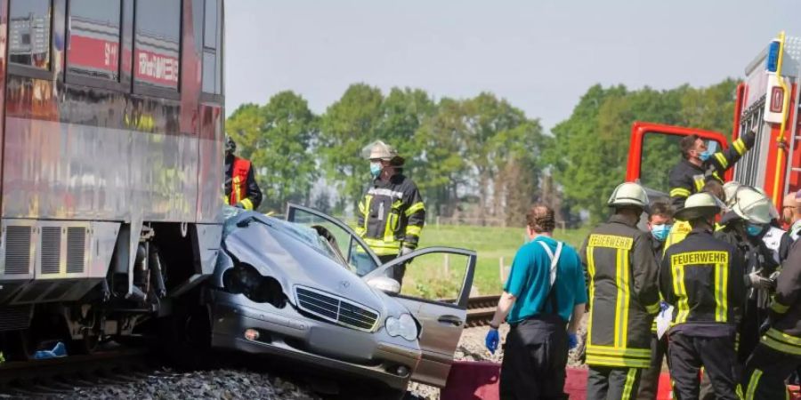 Rettungskräfte stehen an der Unfallstelle. Das Auto wurde von dem Zug etwa 50 Meter mitgeschleift. Foto: Arnulf Stoffel/dpa