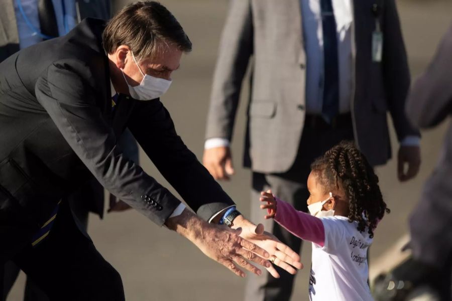 Bei einer Zeremonie am 12. Mai in Brasilia nimmt Jair Bolsonaro ein kleines Mädchen in die Arme.