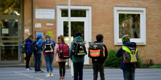 Schulkinder halten Abstand vor dem Eingang. Schulkinder