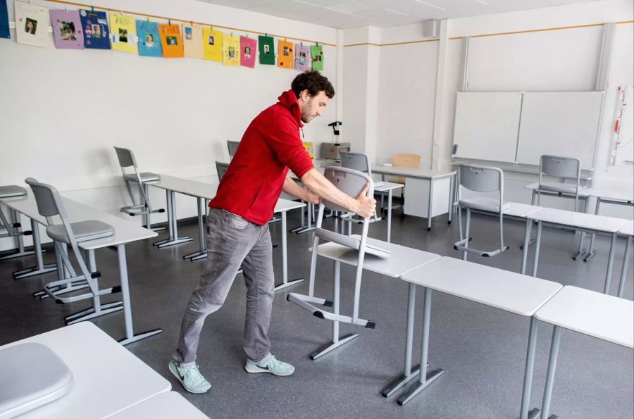 Ein Lehrer bereitet das Schulzimmer für den Unterricht vor.