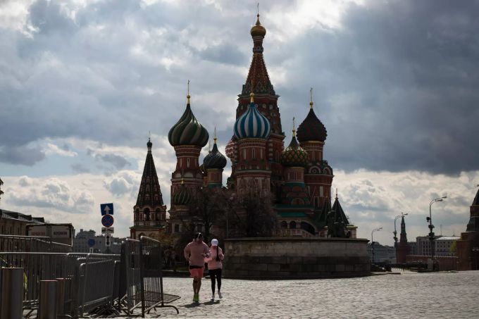 Ein Paar joggt auf dem Roten Platz mit Blick auf die Basilius-Kathedrale. Coronavirus - Russland