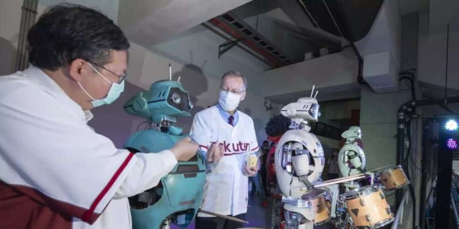 Bürgermeister Cheng Wen-tsan (l) und US-Repräsentant Brent Christensen «füttern» auf der Tribüne im Stadion der «Rakuten Monkeys» Roboter-Trommler mit Schrauben. Foto: -/Taoyuan City Government /dpa