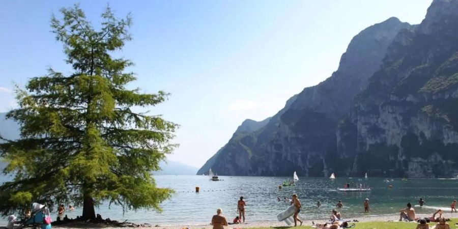 Touristen und Einheimische nehmen am Strand von Riva del Garda ein Sonnenbad (Archiv). Foto: picture alliance / dpa