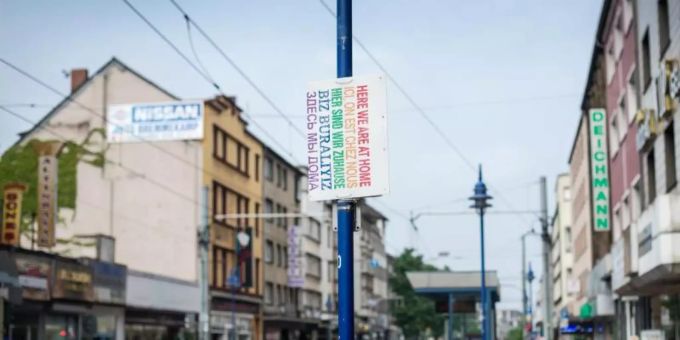 Ein Schild «Hier sind wir zuhause» in verschiedenen Sprachen hängt in Duisburg auf der Strasse. Foto: picture alliance / dpa Ein Schild «Hier sind wir zuhause» in verschiedenen Sprachen hängt in Duisburg auf der Strasse. Foto: picture alliance / dpa