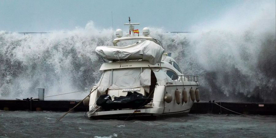 Wellen brechen bei einem Boot im Hafen von Barcelona.