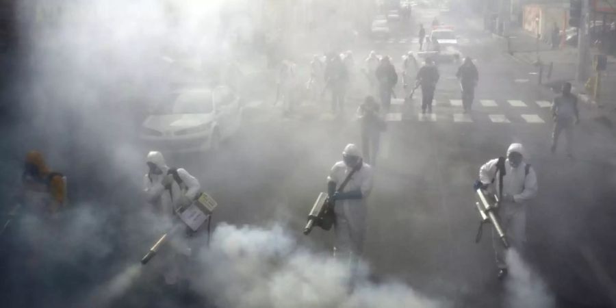 Feuerwehrleute desinfizieren eine Strasse in Teheran