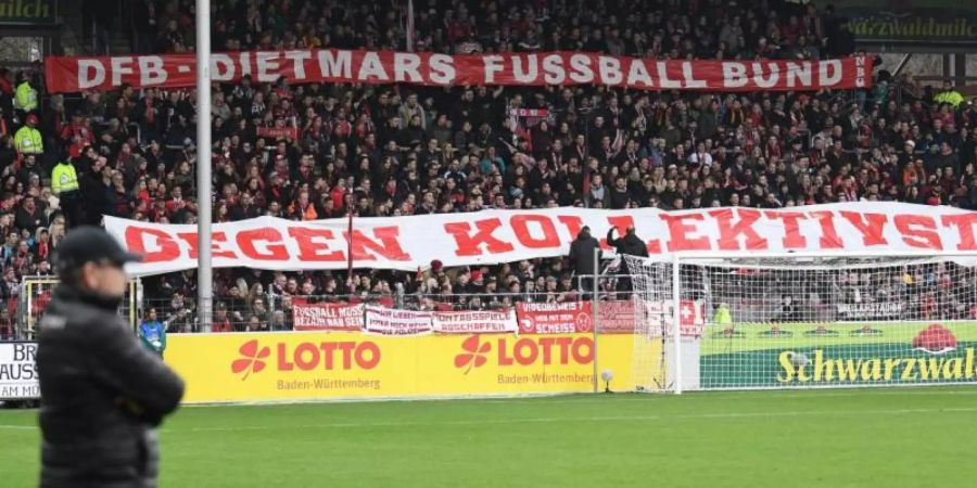 Freiburger Fans halten Banner mit der Aufschrift «DFB - Dietmars Fussball Bund gegen Kollektivstrafen» in die Höhe. Foto: Patrick Seeger/dpa