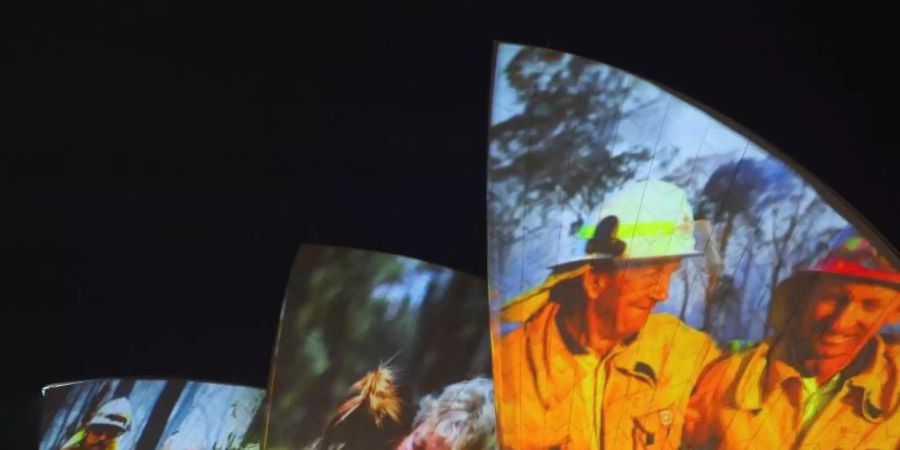 Symbolischer Dank an die Einsatzkräfte in Sydney: Auf die grossen Segel des Opernhauses werden als Zeichen der Solidarität Bilder von Feuerwehrleuten projiziert. Foto: Paul Braven/AAP/dpa