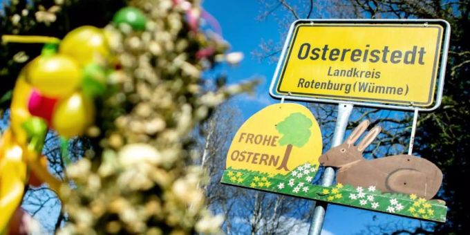 Ein Schild mit der Aufschrift "Frohe Ostern" hängt unter dem Ortsschild am Ortseingang von Ostereistedt. Foto: Hauke-Christian Dittrich/dpa