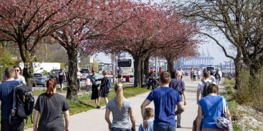 Osterausflügler gehen bei strahlendem Sonnenschein an der Elbe entlang. Foto: Axel Heimken/dpa