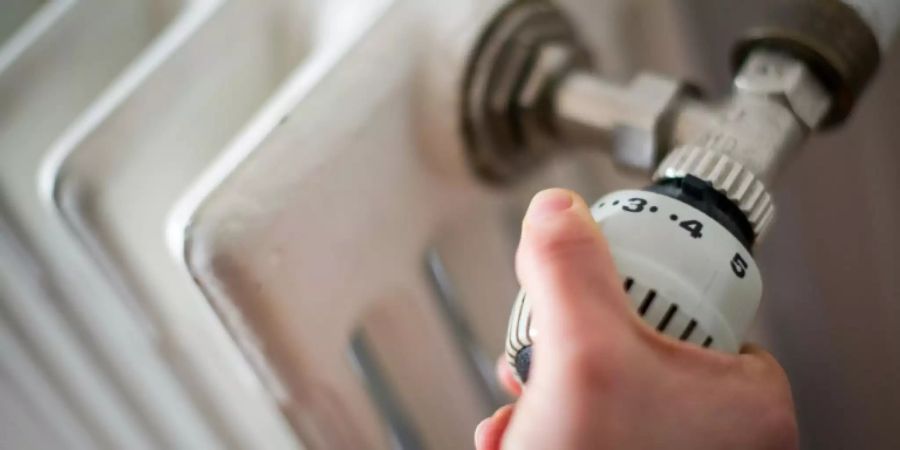 Frau am Thermostat einer Heizung