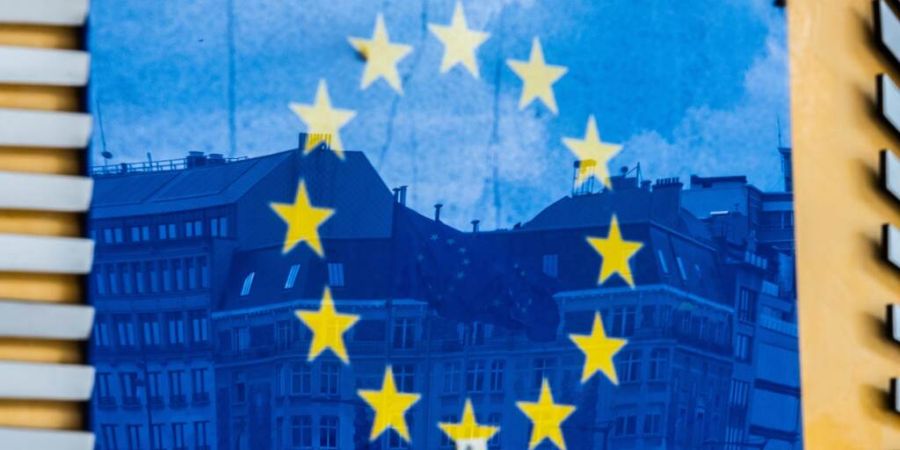 ARCHIV - Drei Fahnen der Europäischen Union und gegenüberliegende Gebäude spiegeln sich im EU-Logo an der Außenfassade des Berlaymont-Gebäudes. Foto: Alicia Windzio/dpa