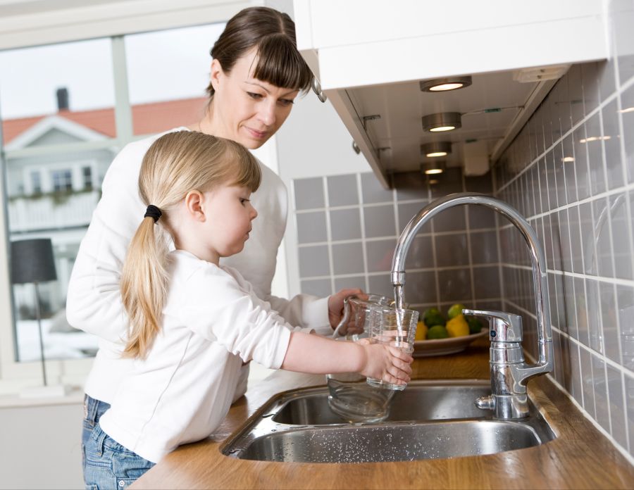 Kind befüllt Glas mit Wasser