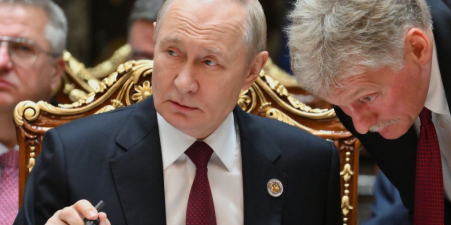 ARCHIV - Der russische Präsident Wladimir Putin (l) spricht mit Kreml-Sprecher Dmitri Peskow während des Gipfels der Gemeinschaft Unabhängiger Staaten im Palast der Nation. Foto: Gri...