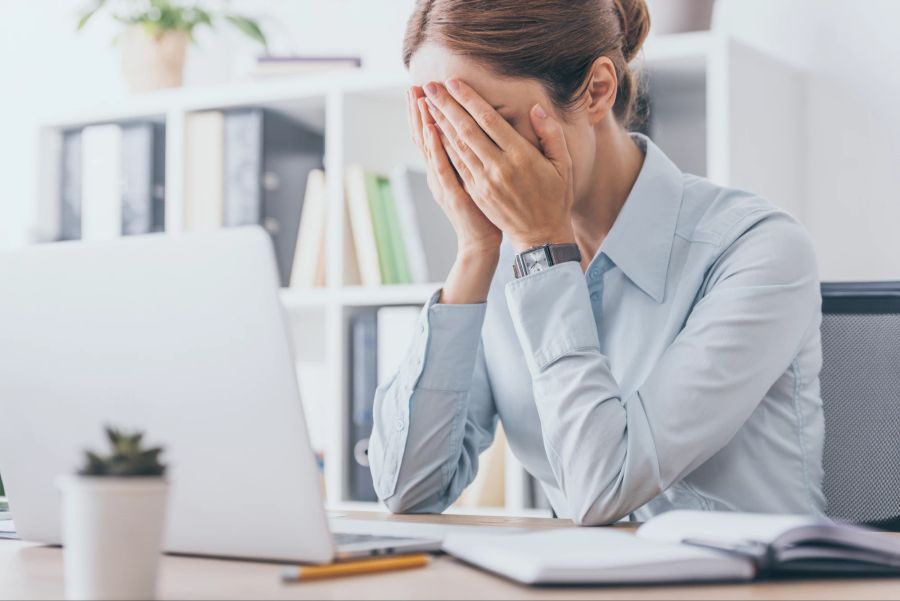 Gestresste erwachsene Geschäftsfrau bedeckt Gesicht im Büro.