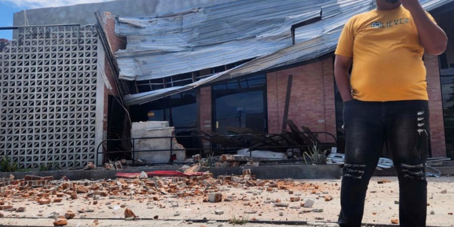 dpatopbilder - Ein Mann telefoniert mit seinem Handy in der Nähe eines durch ein Erdbeben beschädigten Gebäudes in Palu, Zentral-Sulawesi. Foto: Josua Marunduh/AP/dpa
