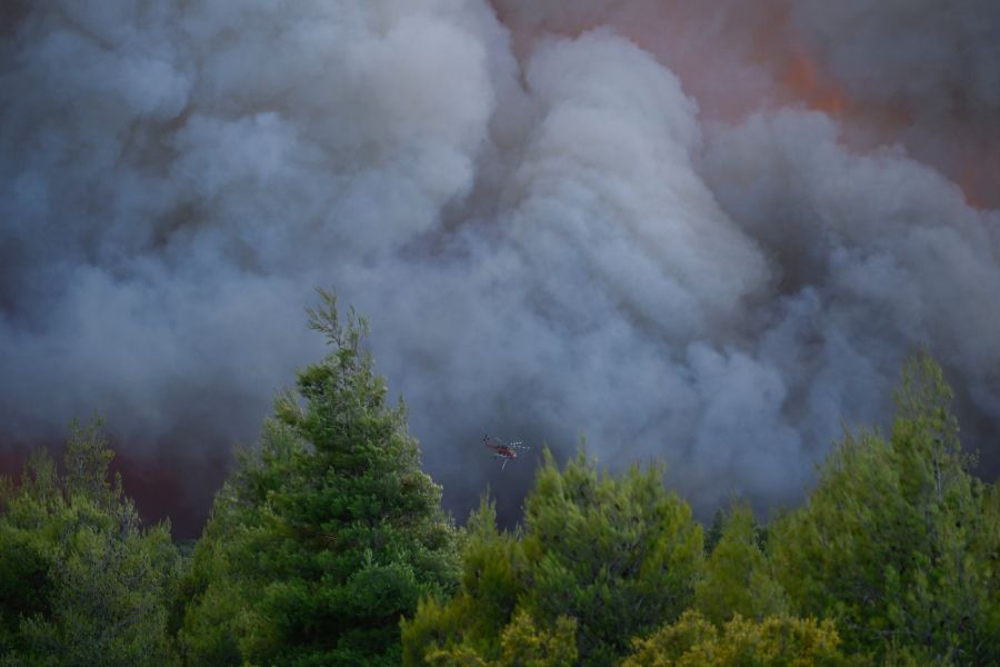 Ein Löschhelikopter fliegt durch dichten Rauch, während er im Einsatz gegen die Flammen ist.