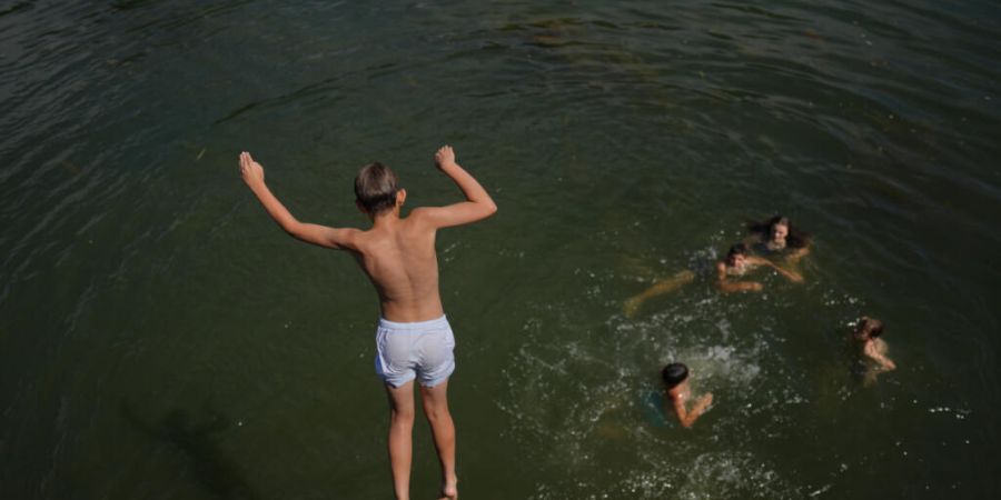 Ein Junge springt in die Seine. Foto: Thibault Camus/AP/dpa