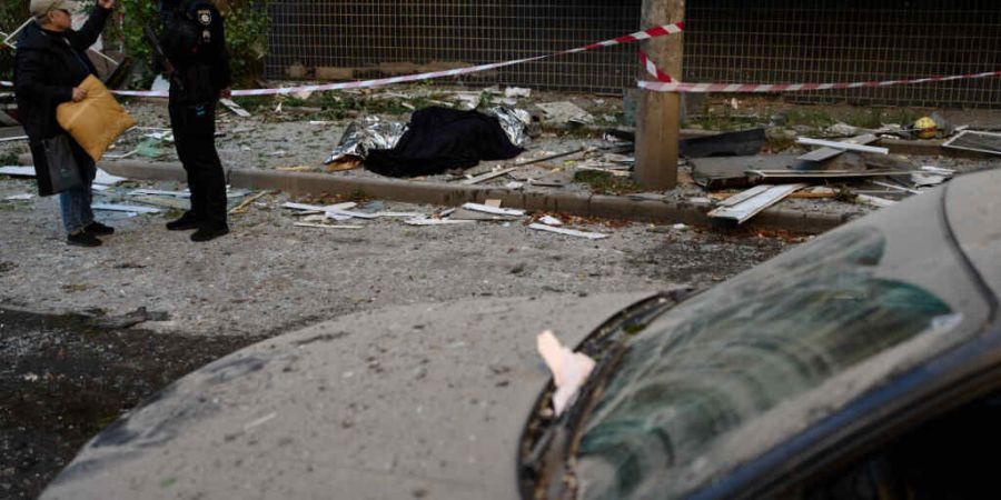 dpatopbilder - Ein Polizist spricht mit einem Anwohner neben den Leichen zweier Menschen, die bei einem nächtlichen russischen Angriff ums Leben gekommen sind. Foto: Francisco Seco/AP/dpa