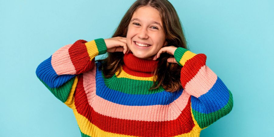 Lächelnde junge Frau trägt bunten Colorblock-Pullover