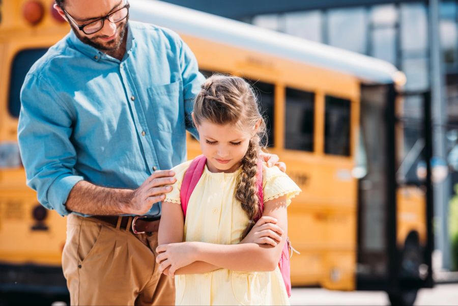 Vater und traurige Tochter am Schulbus.