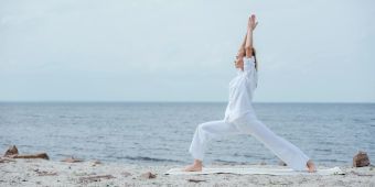 Frau macht Yoga am Strand.