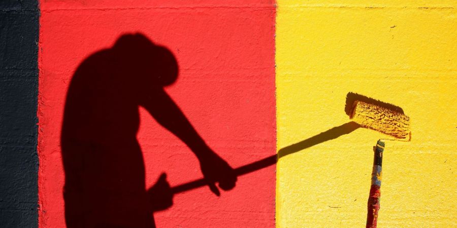 Heute Abend geht es los! Ein Helfer lackiert Kurvensteine in den Farben Schwarz-Rot-Gold.